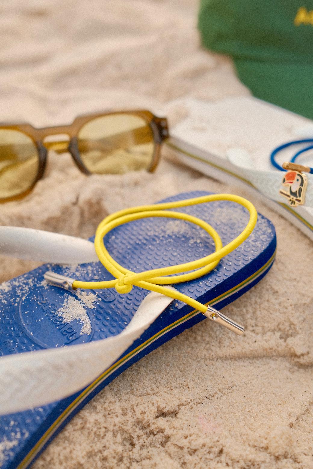 Yellow Loopi hair tie with sunglasses on the beach